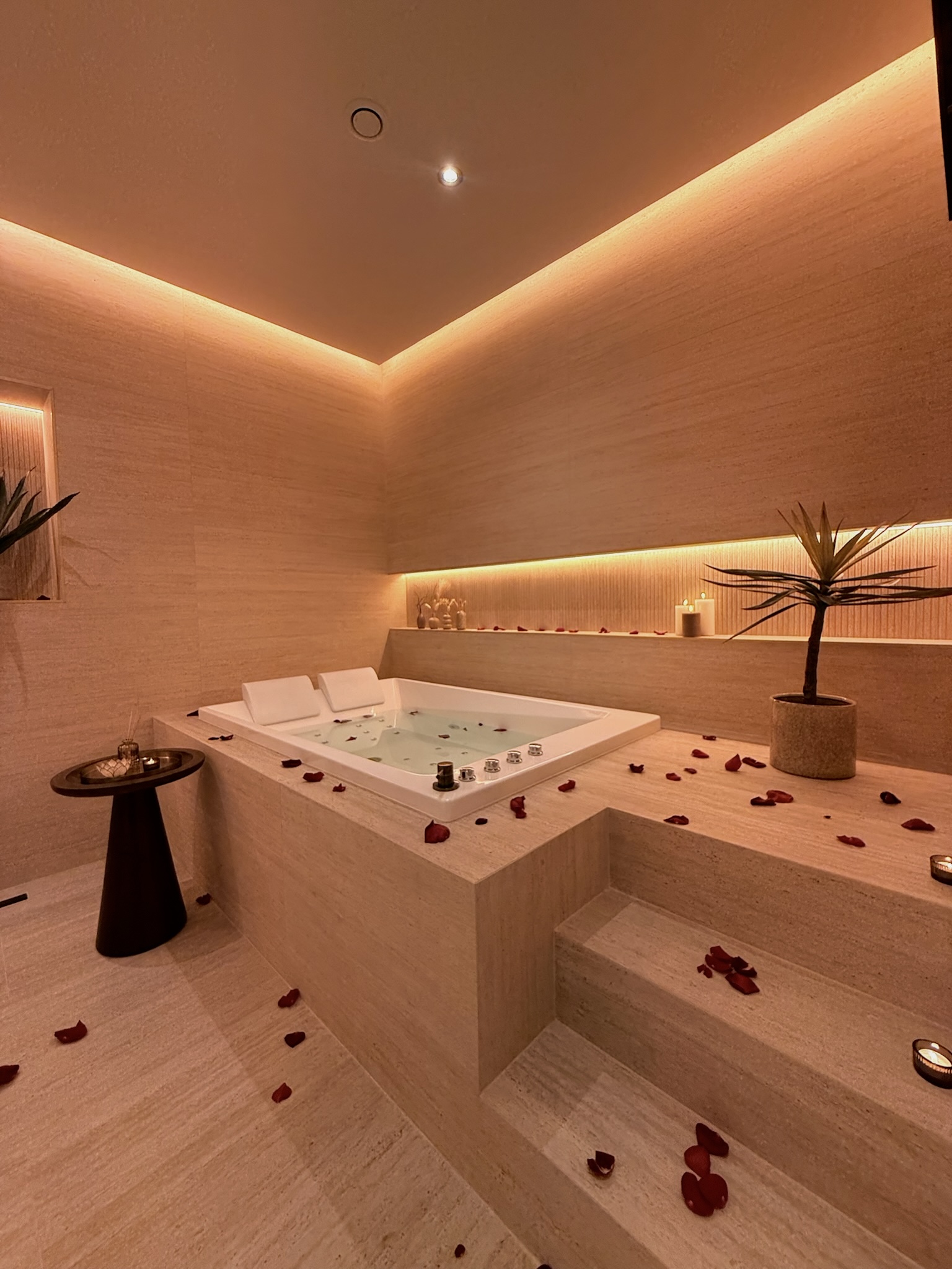 Jacuzzi en travertin clair sous la niche rétroéclairée — Maison Nina N°5, Argenteuil