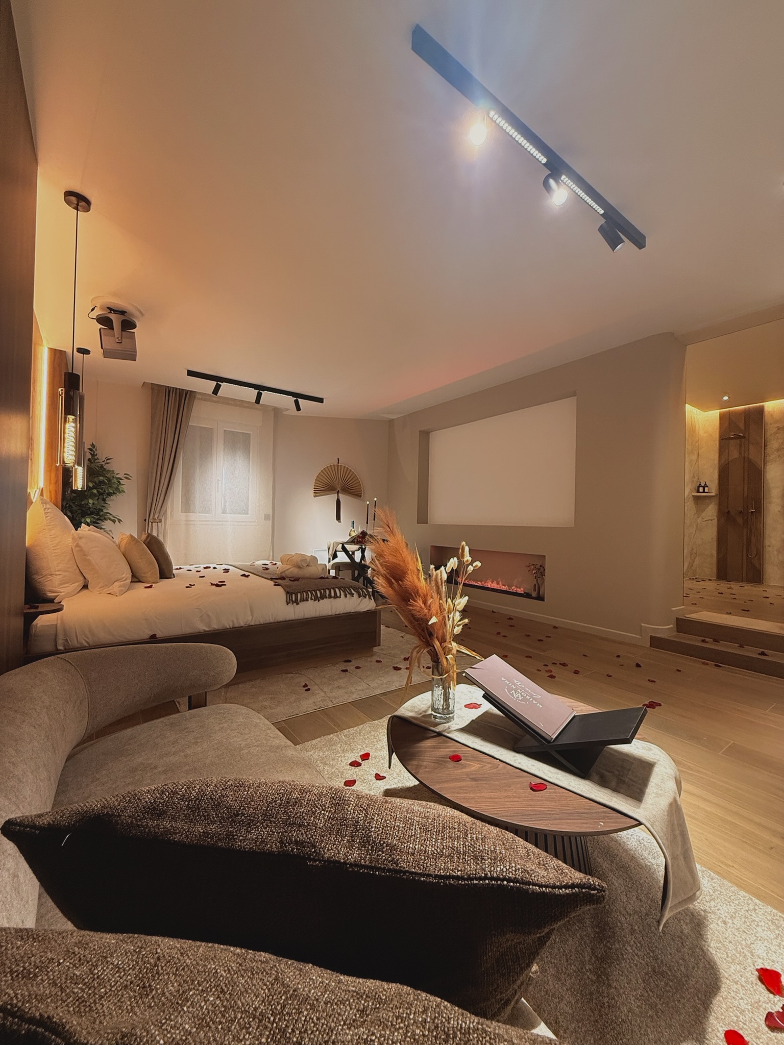 Écran géant et cheminée à vapeur face au lit — cinéma 4K en suite privative à Argenteuil