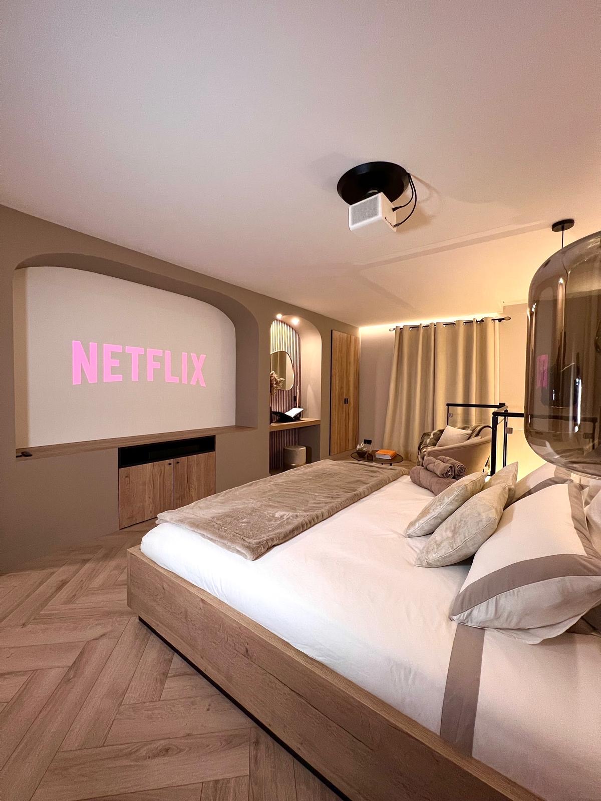Vidéoprojecteur au plafond au-dessus du lit King size — espace cinéma de la suite Maison Nina N°1